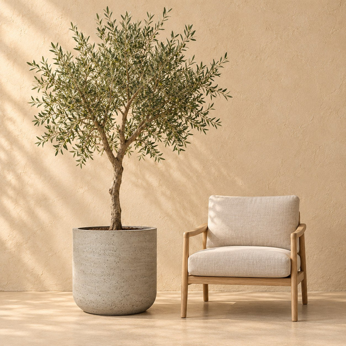 Dekorativ potte Charlie Beige Washed Ø53 x H52 cm, i naturlig størrelse ved siden af en lænestol