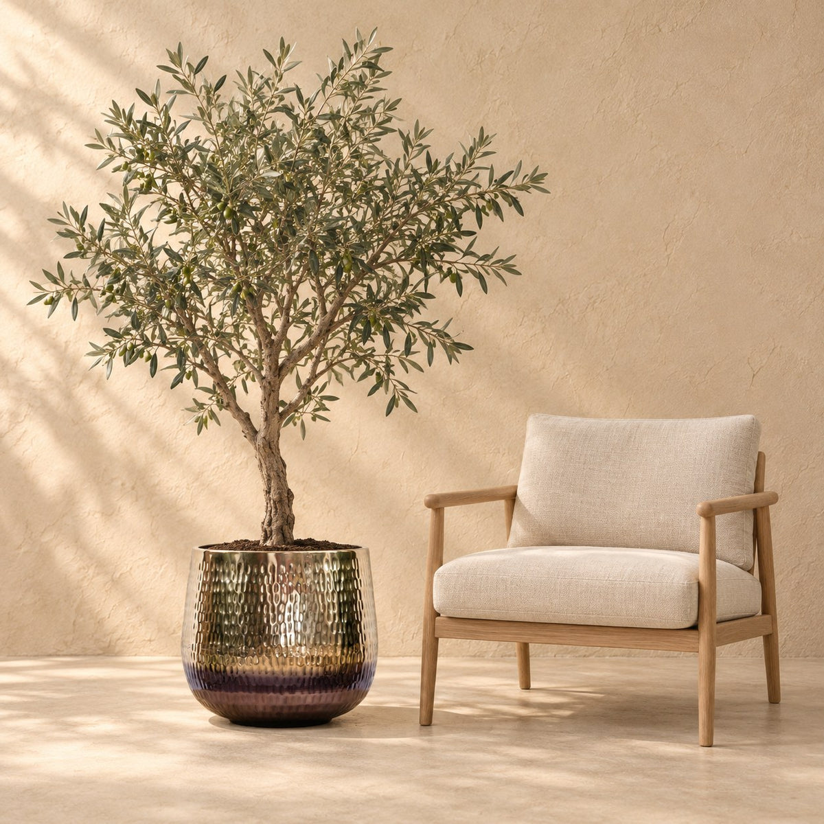 Pot décoratif Jenna doré Ø46 x H38 cm, à taille réelle à côté d’un fauteuil