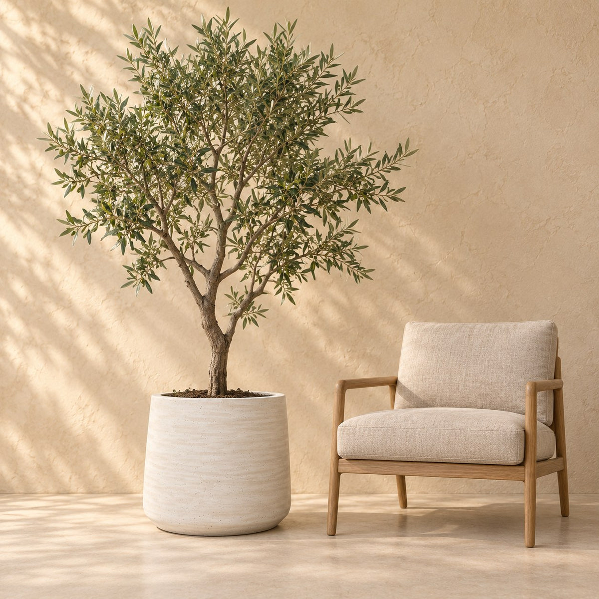 Dekorativ potte Patt Beige Washed Ø56 x H47 cm, i naturlig størrelse ved siden af en lænestol